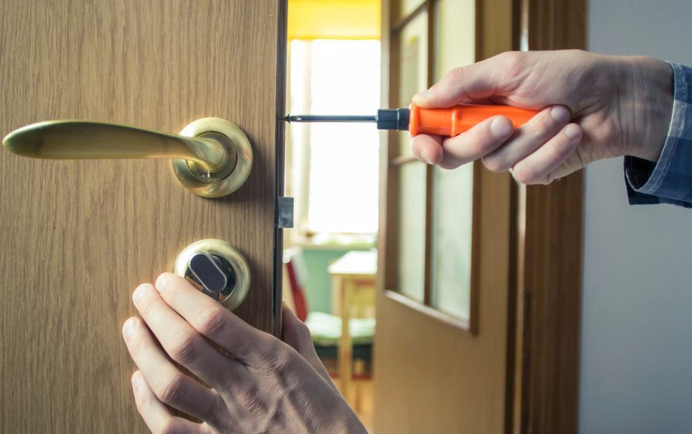 A person is fixing a door with a screwdriver — Locksmith in Helensvale, QLD