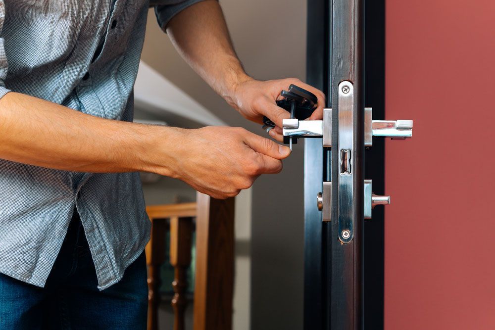A man is fixing a door with a screwdriver — Locksmith in Southport, QLD