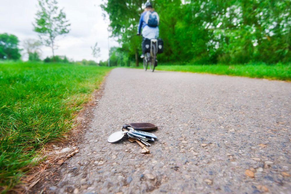 A person riding a bike down a path with keys on the ground — Locksmith in Helensvale, QLD