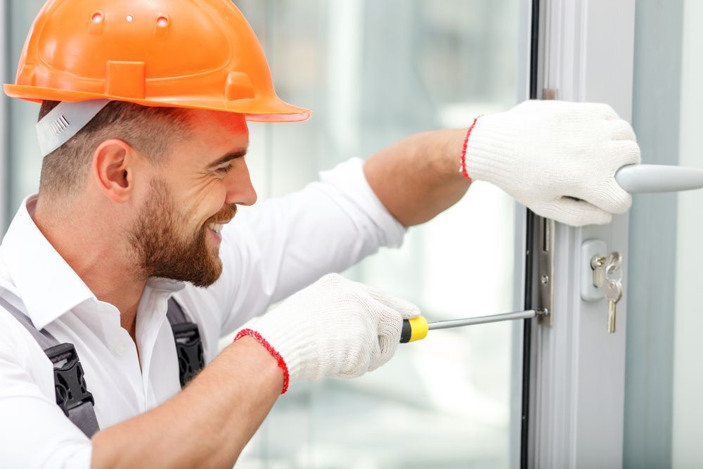A man wearing a hard hat is working on a door lock — Locksmith in Currumbin, QLD