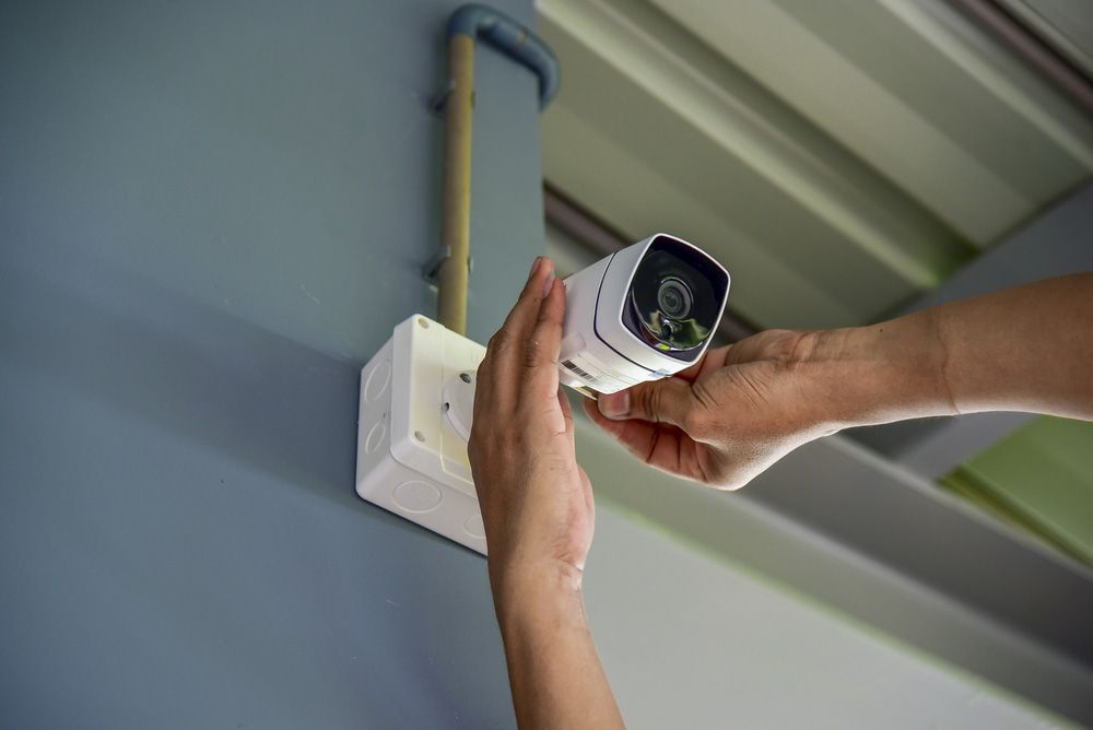 Person is installing a security camera on a wall — Locksmith in Tweed Heads, NSW
