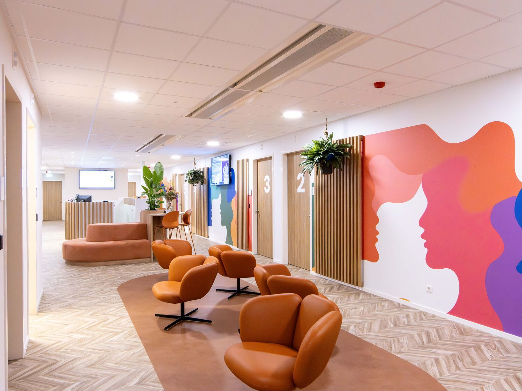 Moderne lobby met beige loungestoelen, potplanten en een kleurrijke abstracte muurschildering.