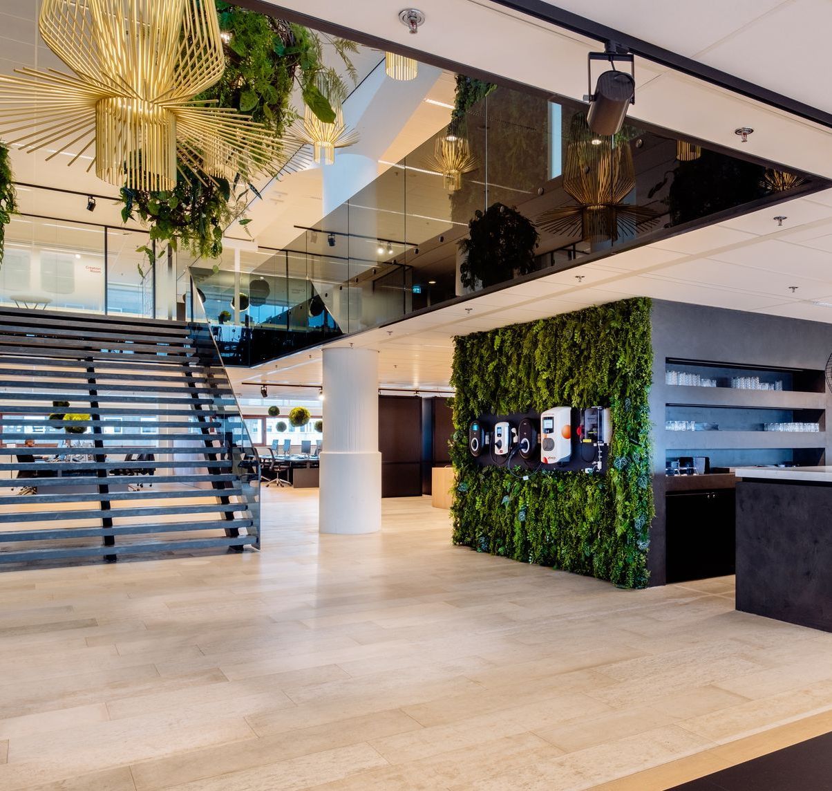 Een lichte, moderne kantoorlobby van Eneco eMobility in Rotterdam met een royale trap, weelderige groene planten en een gouden kroonluchter.