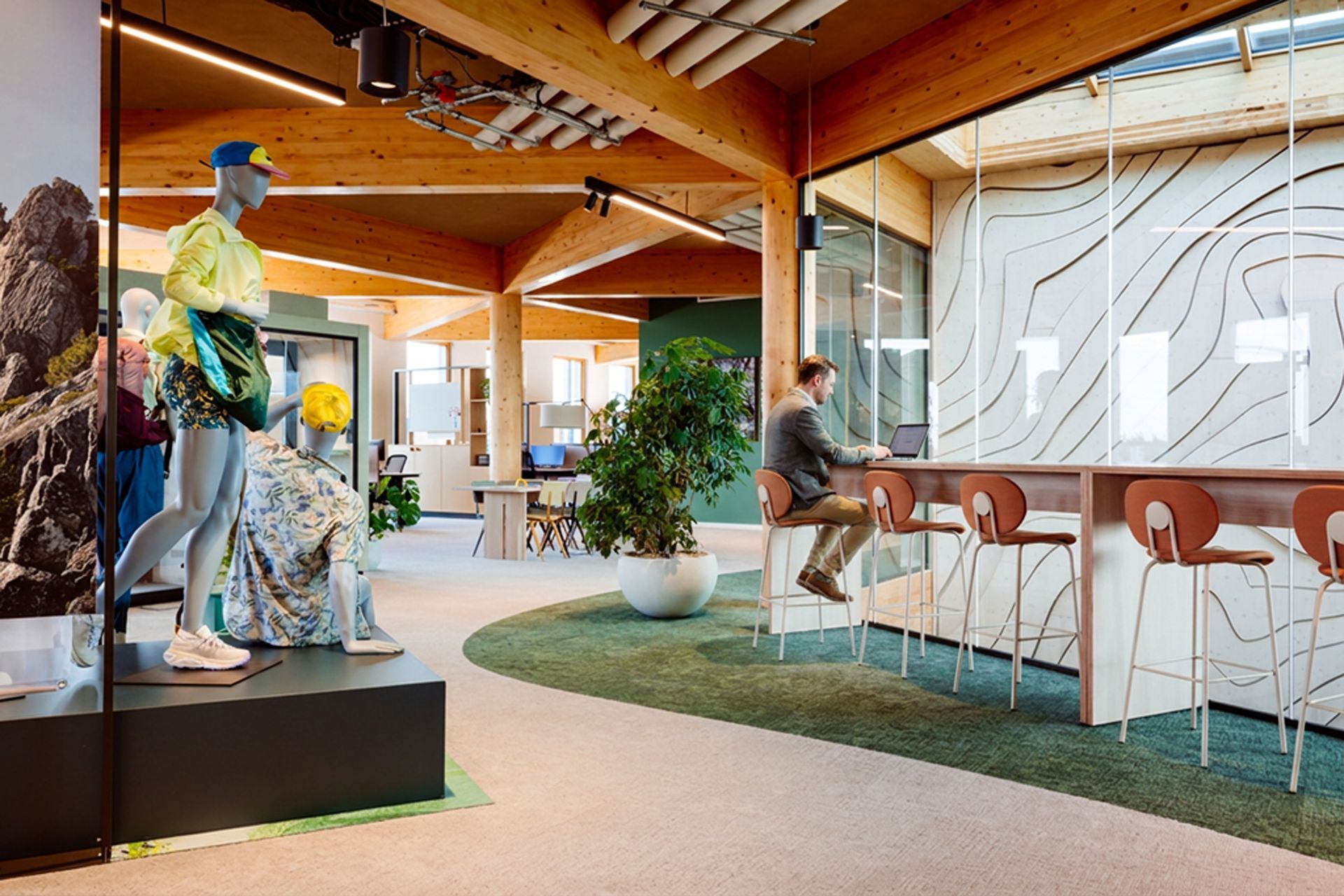 Moderne kantoorlobby met een sculptuur, zitgelegenheid, planten en een gebogen glazen wand.