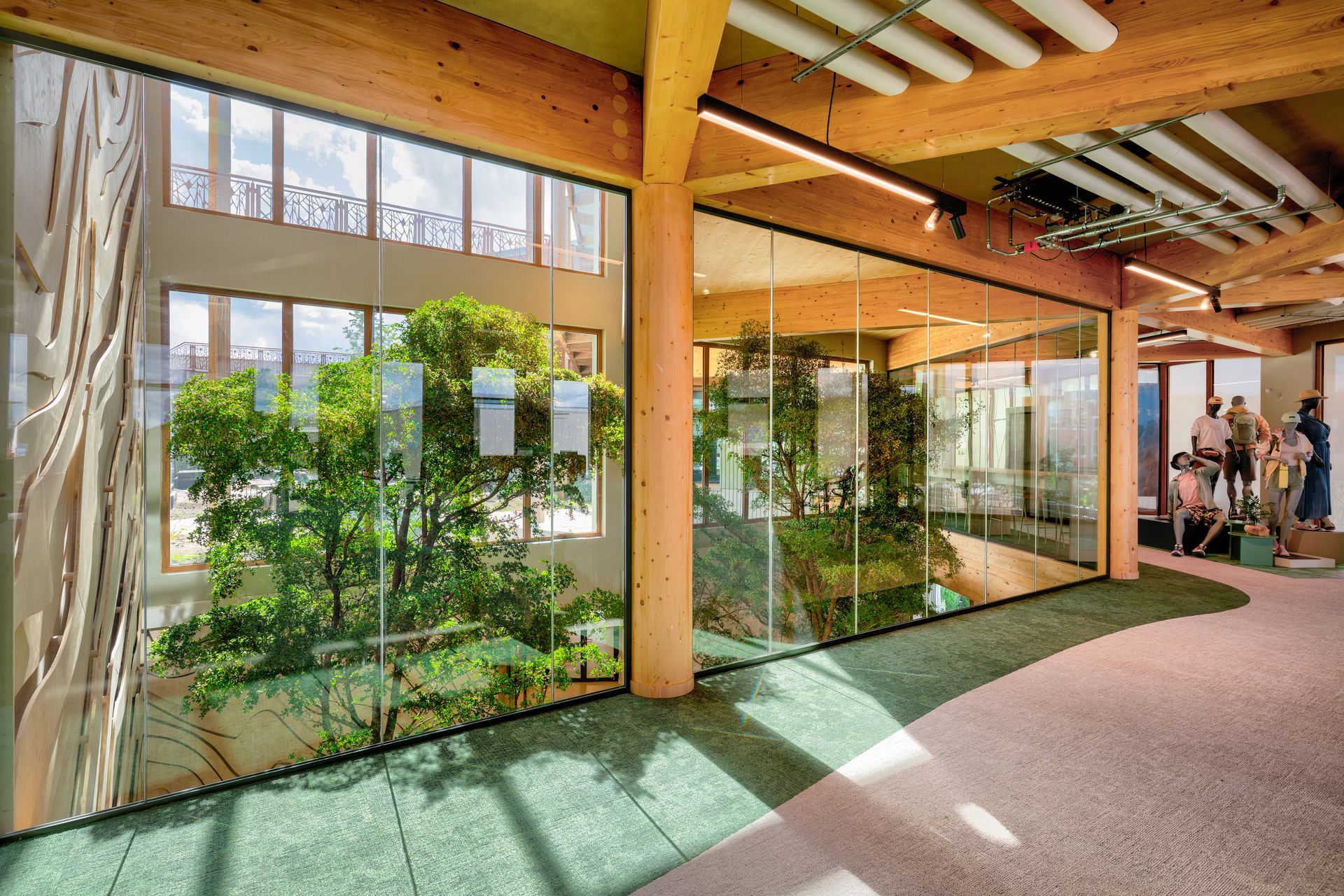 Een modern interieur met glazen wanden die uitzicht bieden op kamerplantenen  houten balken, tapijt in biophilic partroon  in het nieuwe kantoor van Bever, interieurontwerp door KuóStudio