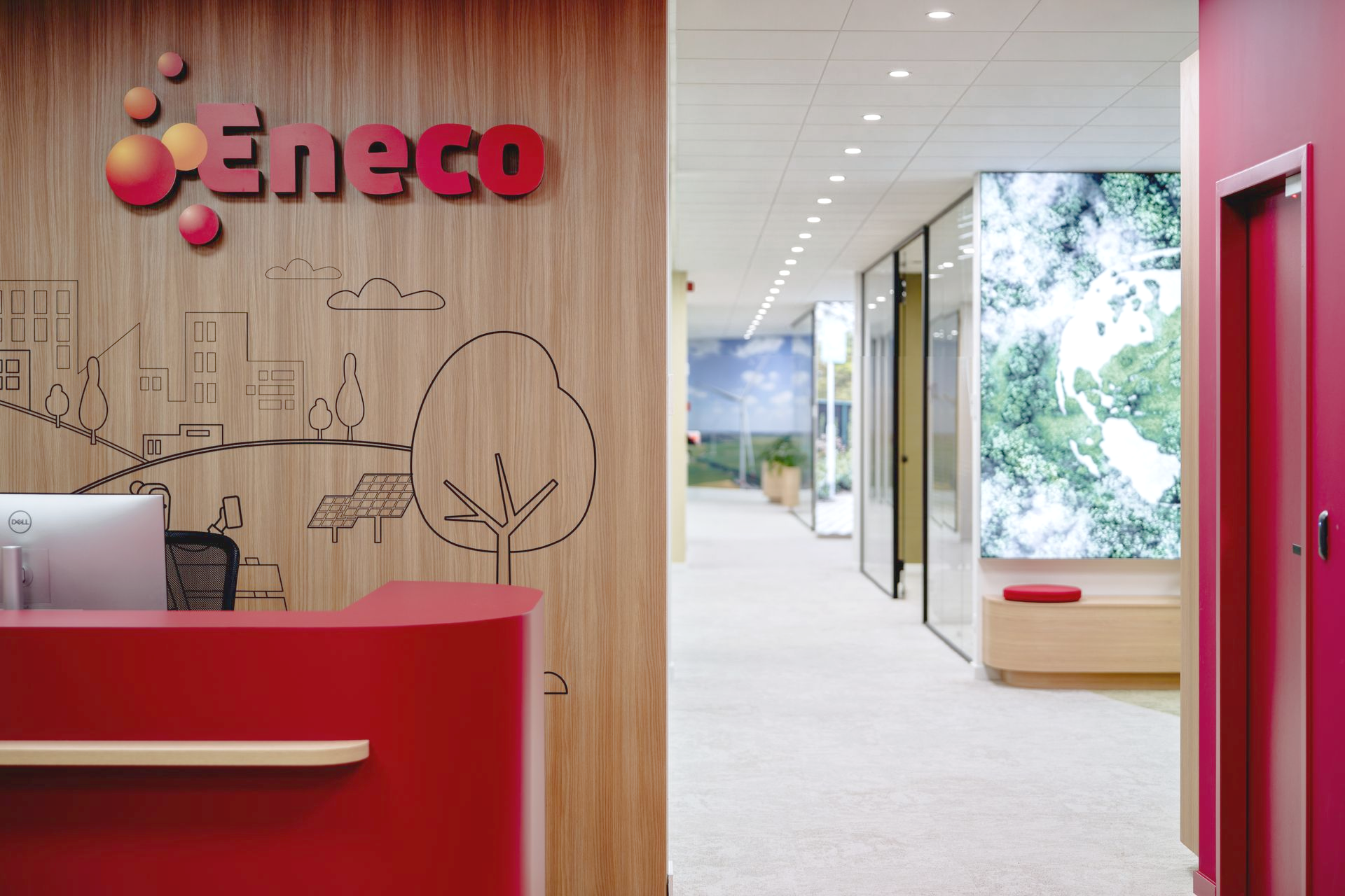 Moderne kantoorentree met rode receptiebalie en Eneco-logo op houten wand.
