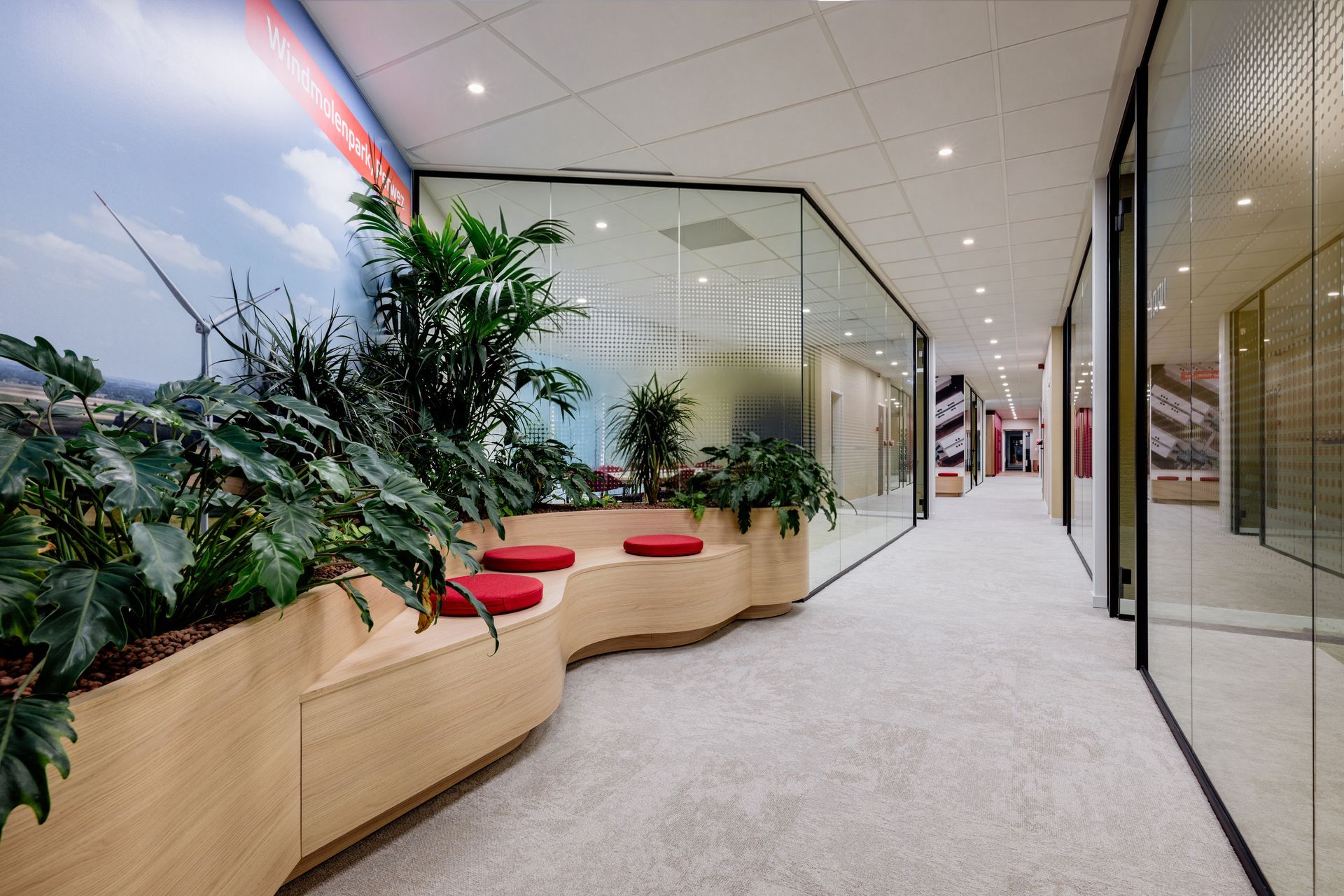 Entree kantoor van Eneco Belgium met rode receptiebalie, zittende gast en een felgekleurd Eneco-logo aan de muur.