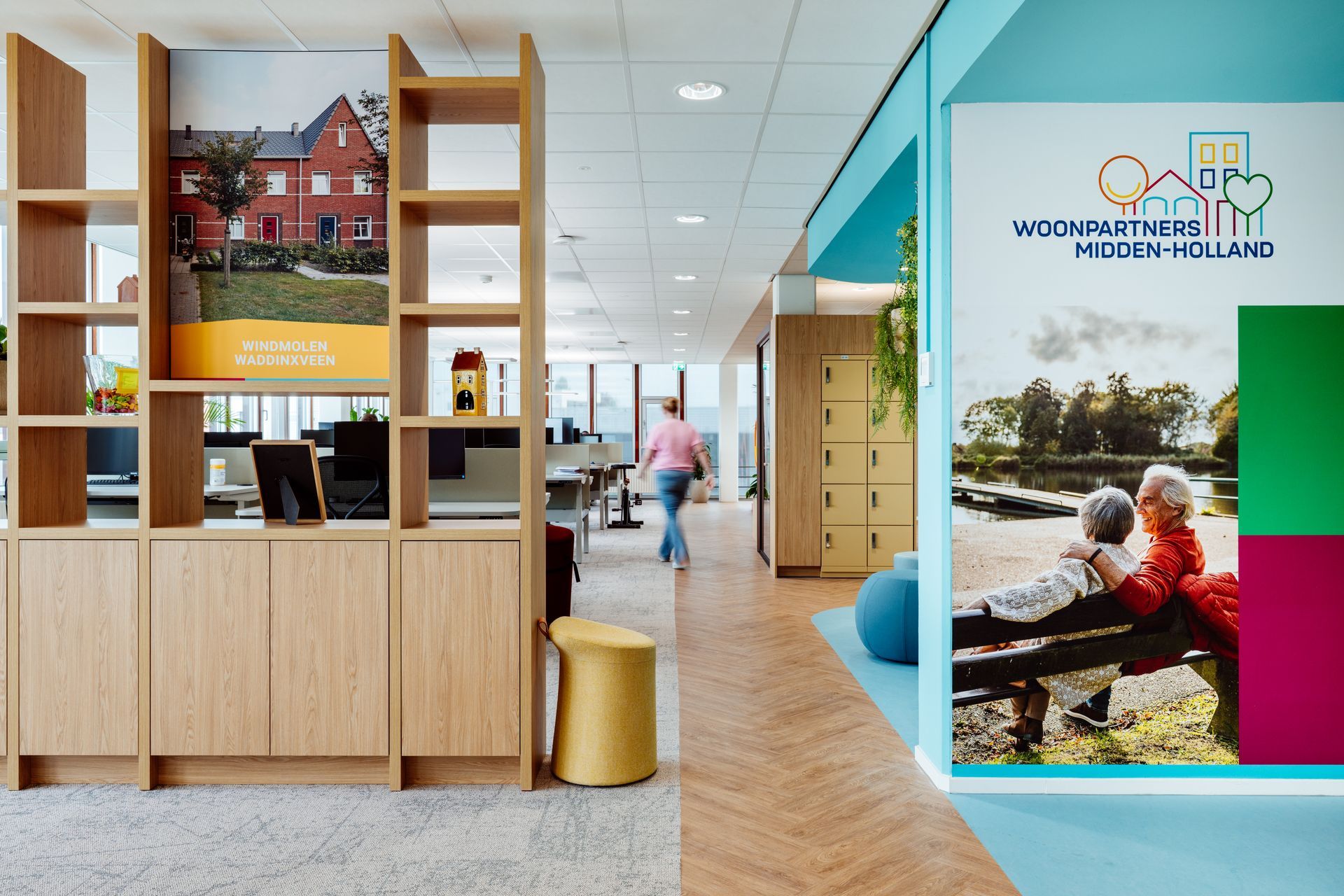 Moderne kantoorlounge met houten planken, een turquoise muur en een kleurrijke fotomuur.