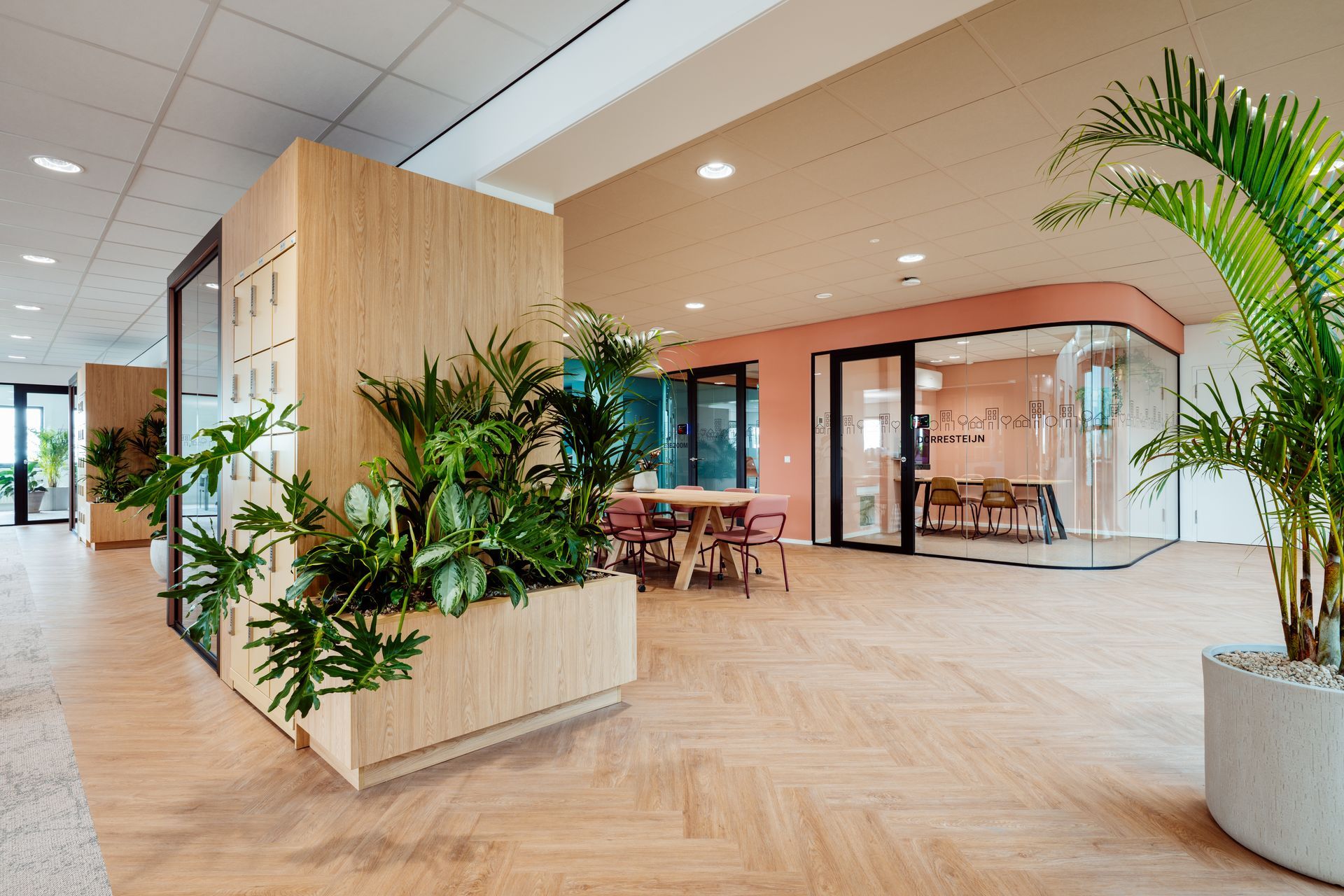 Lichte, moderne kantoorlobby met houten vloeren, potplanten en een zithoek.