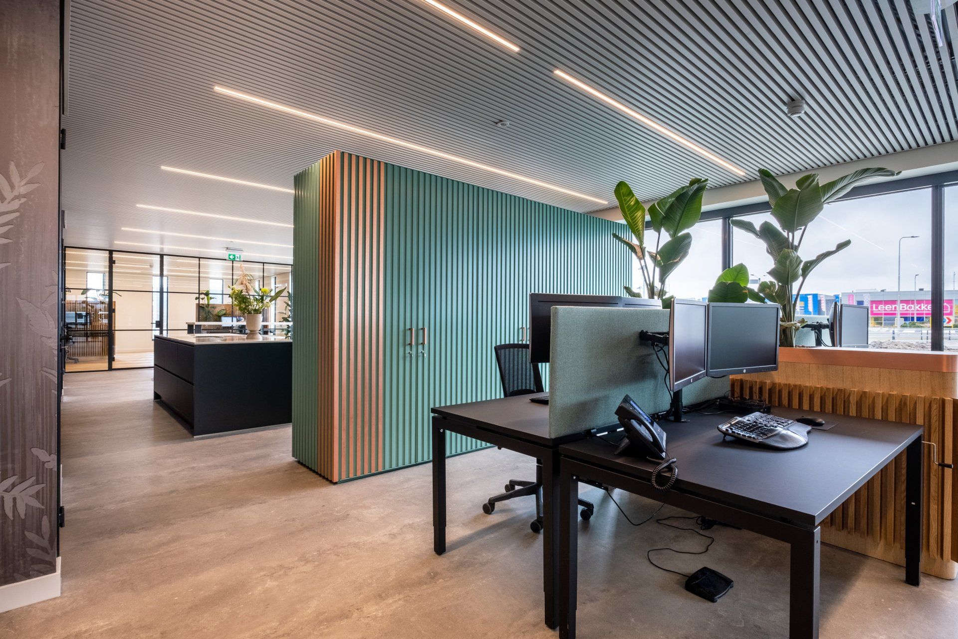 Modern kantoor van EBH Legal in Naaldwijk met strakke zwarte bureaus, groene geluidsisolerende scheidingswanden, potplanten en een unieke maatwerk kast ontworpen door KuóStudio.