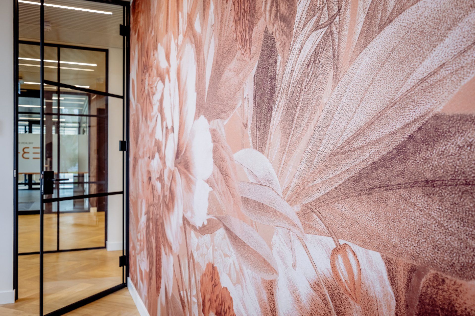 Modern office hallway with a large pink abstract mural and glass-walled rooms.
