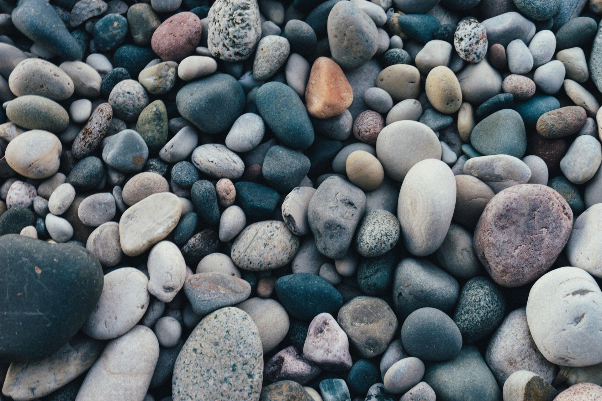 A pile of rocks of different sizes and colors on a beach.