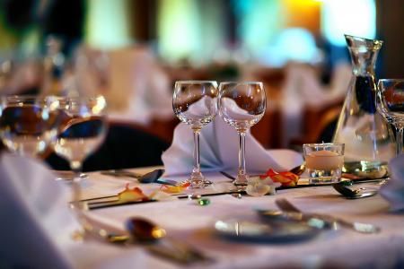 Set dining table with wine glasses, plates, and a water carafe at a softly lit restaurant