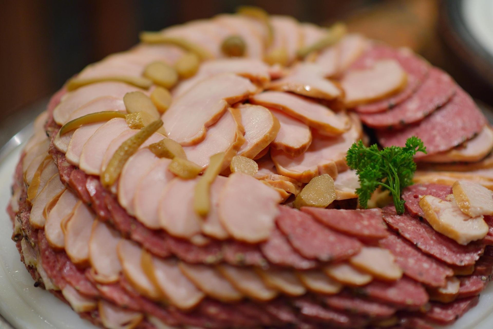 Platter of layered sliced meats garnished with parsley and onions
