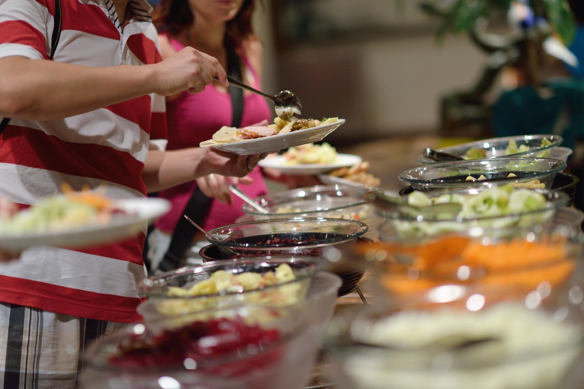 Buffet table with people serving themselves food from various dishes in a casual dining setting