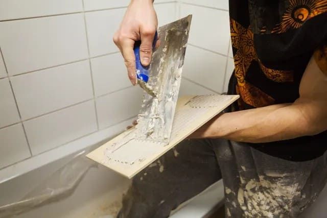 Fliesenleger trägt Masse auf Fliese auf
