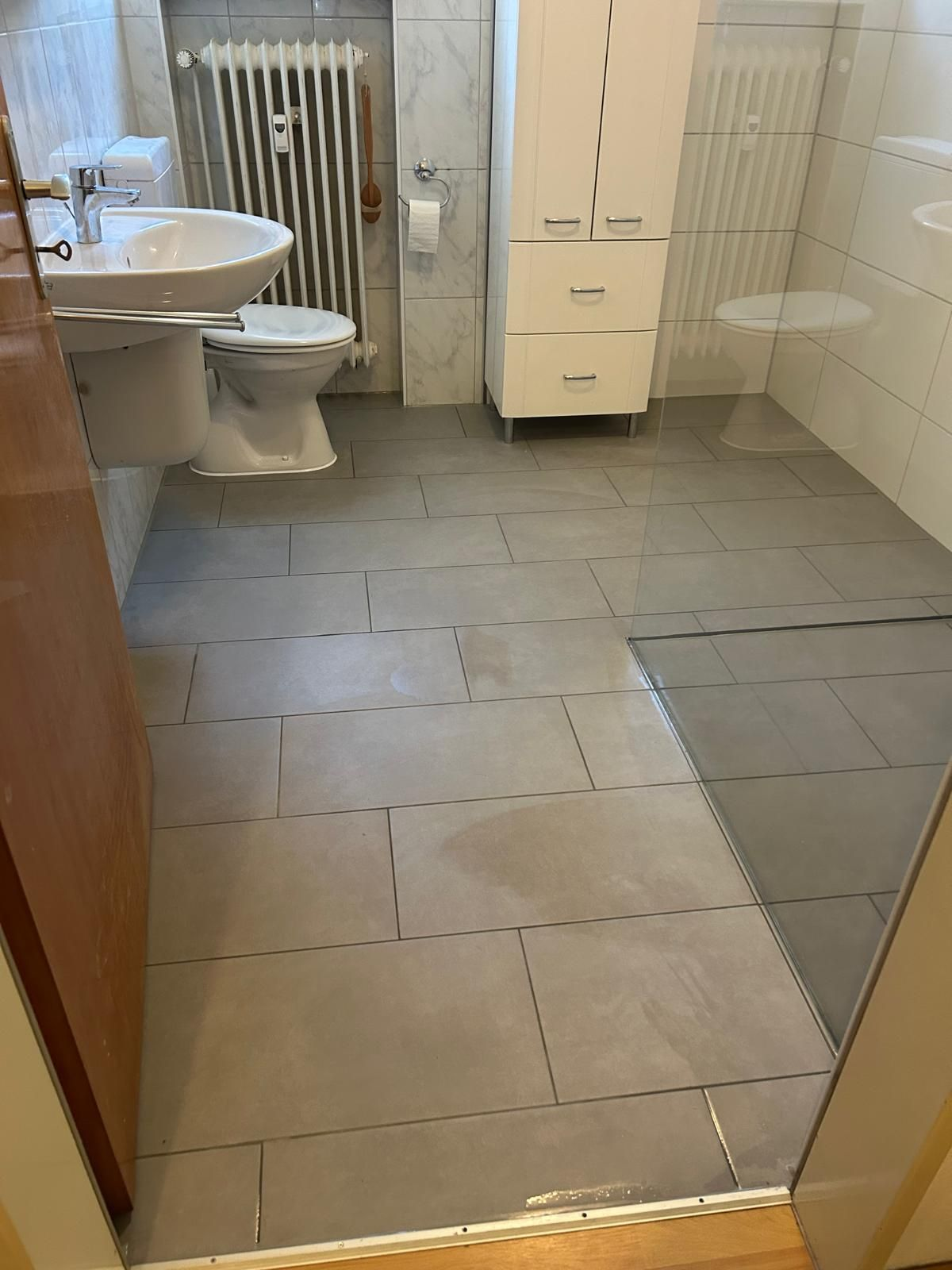 Barrierefreies Badezimmer mit schwellenlosem Zugang, rutschhemmenden Bodenfliesen, wandhängendem Waschbecken und ebenerdiger Dusche Barrierefreies Badezimmer: schwellenloser Zugang, rutschhemmenden Bodenfliesen, wandhängendem Waschbecken, ebenerdiger Dusche