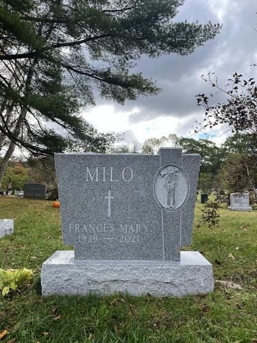 Gravestone in cemetery, gray granite with etched cross and figures. 