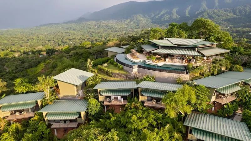 An aerial view of a hotel surrounded by trees and mountains.