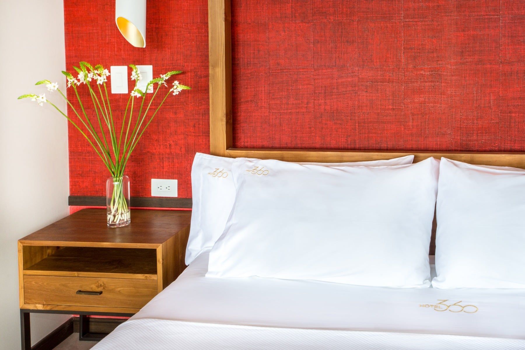 There is a vase of flowers on the nightstand next to the bed.