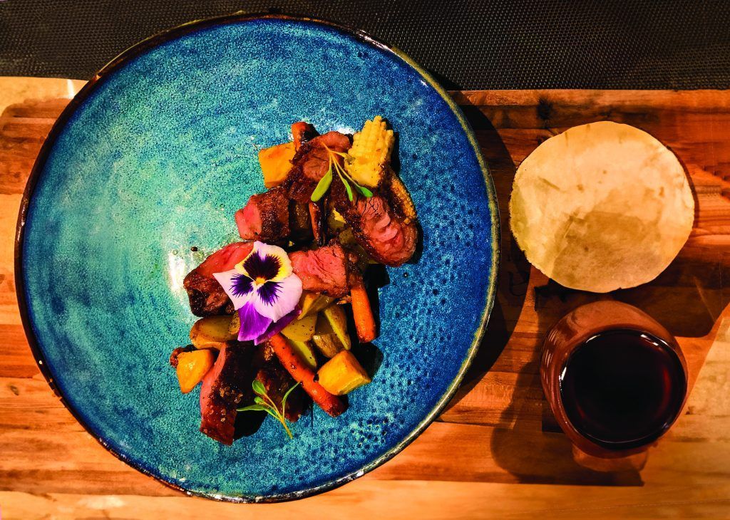 A plate of food is sitting on a wooden table next to a cup of coffee.