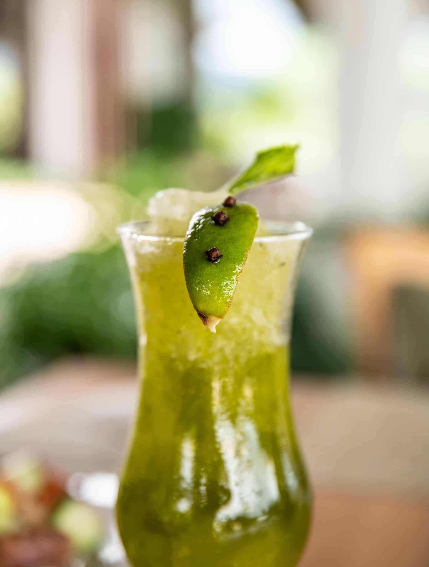 A close up of a green drink in a glass on a table.