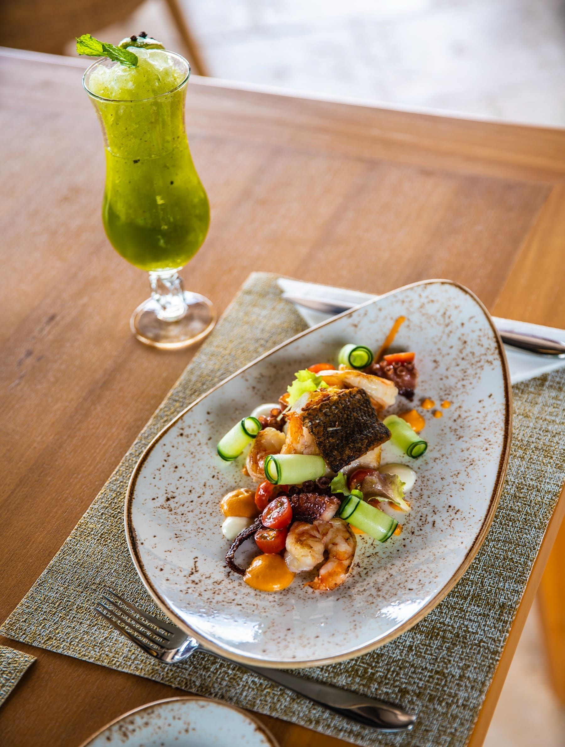 A plate of food and a drink on a table.