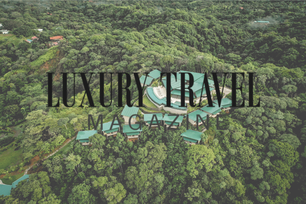 An aerial view of a lush green forest with the words luxury travel magazine written above it.