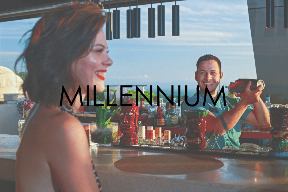 A woman is sitting at a bar with a man behind her holding a drink.