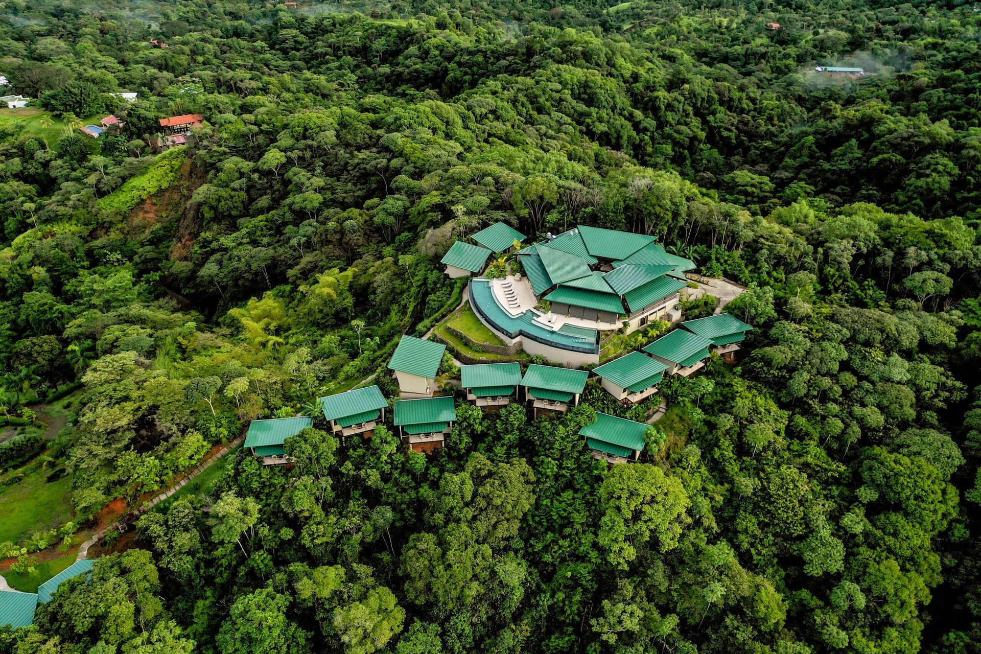 An aerial view of a hotel in the middle of a lush green forest.