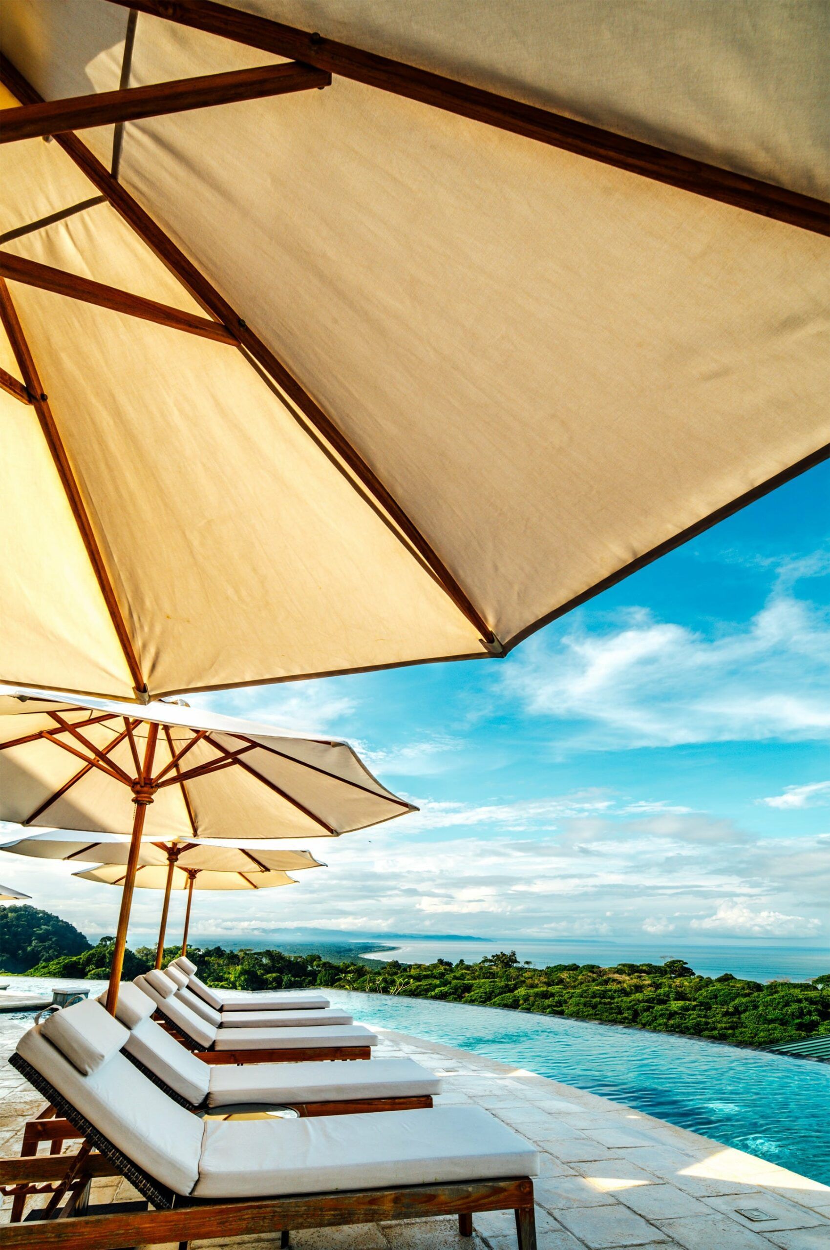 A row of lounge chairs under umbrellas next to a swimming pool