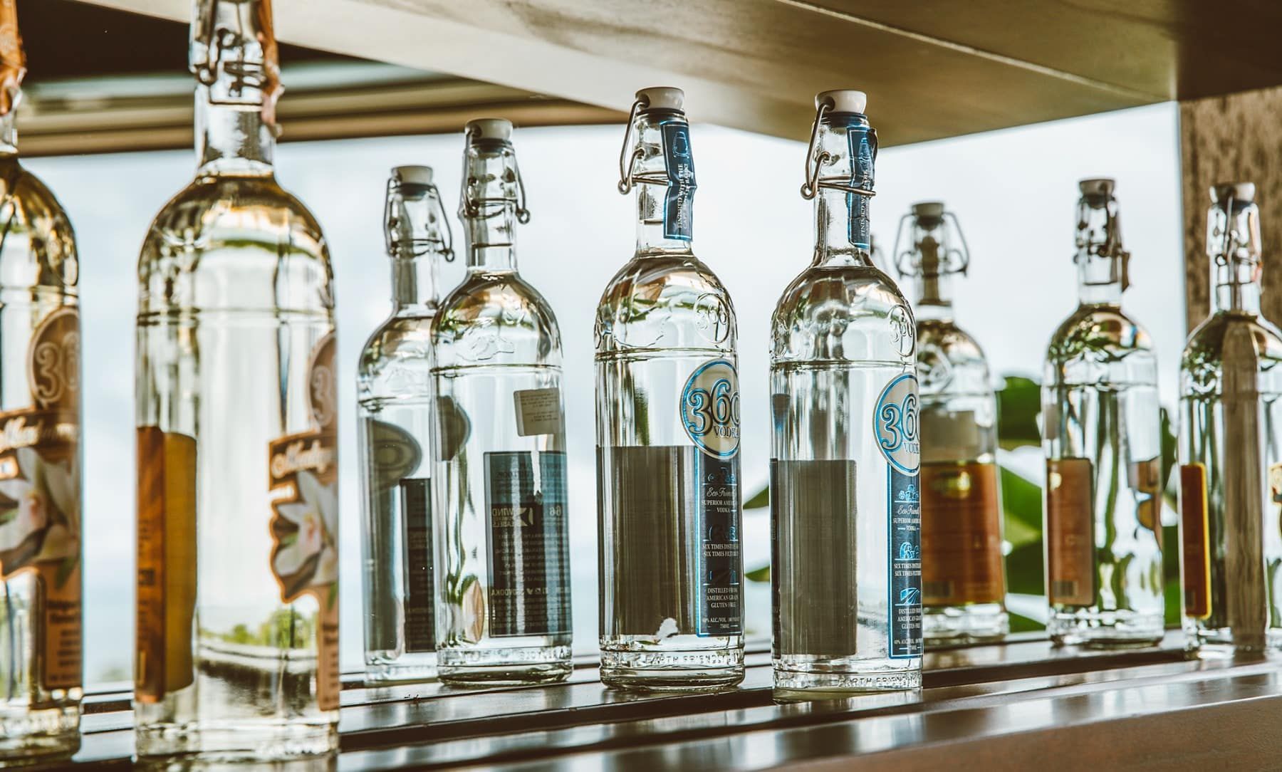A row of bottles of alcohol are lined up on a shelf.