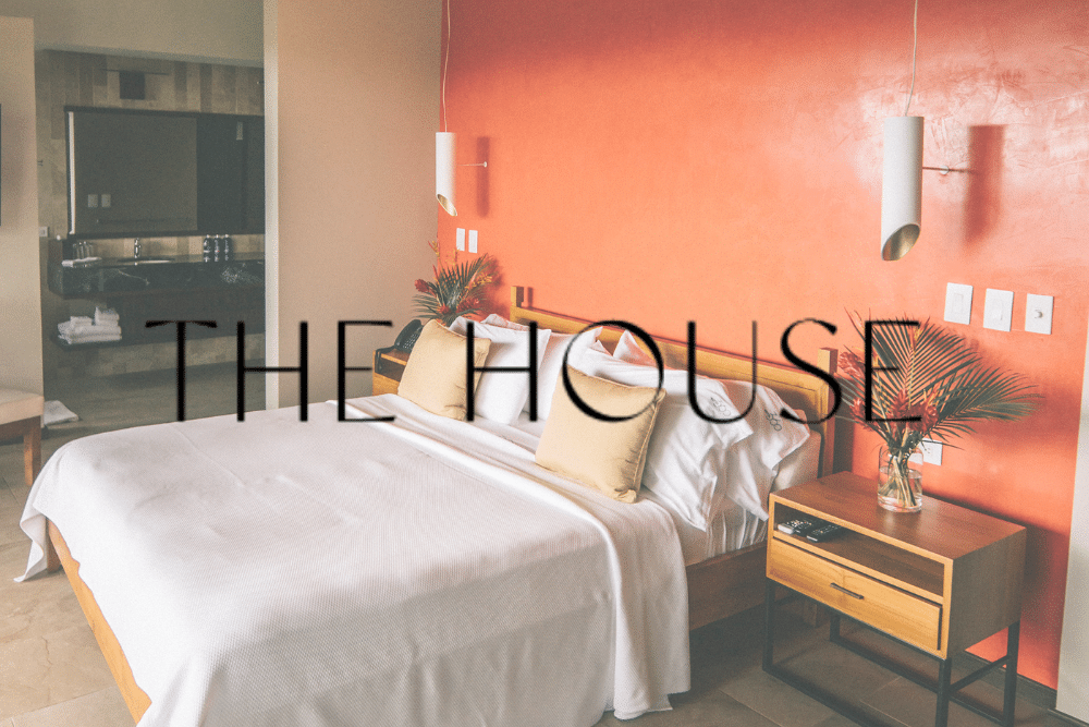 A bedroom with a bed and a nightstand with the words the house written on it.