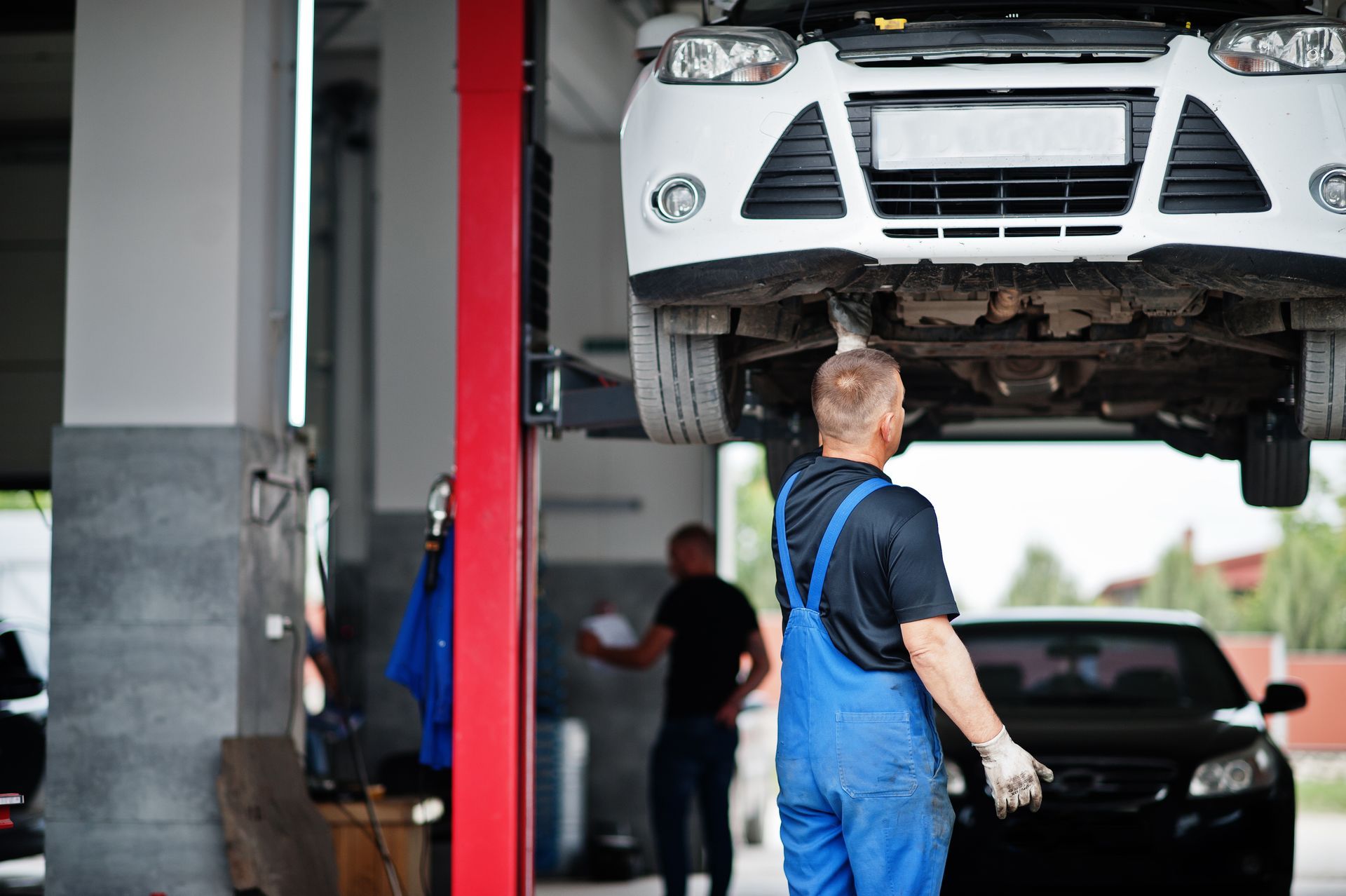 Mechanic inspecting a lifted car in a garage before transmission repair in O'Fallon, MO