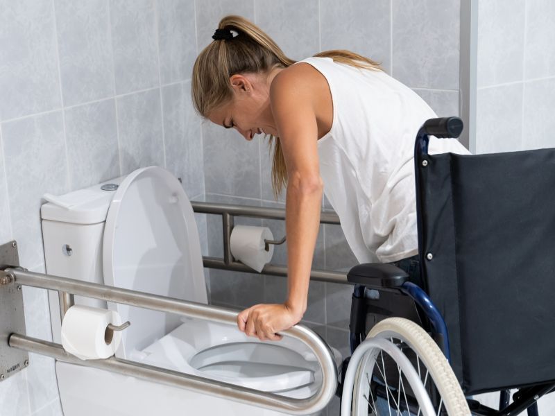 Woman using frame to get onto toilet