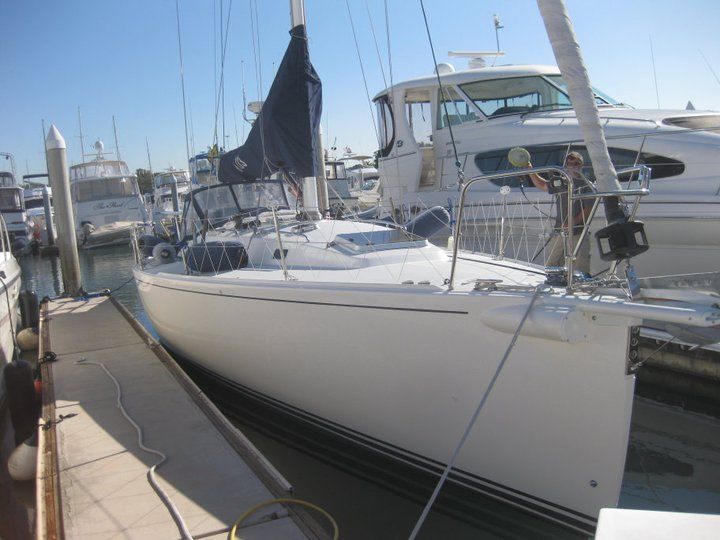 A sailboat is docked in a marina with other boats