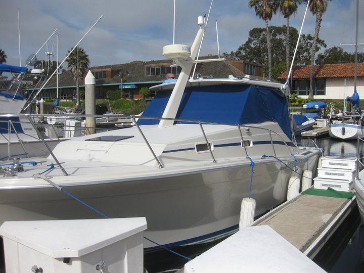 A boat with a blue canopy is docked in a marina