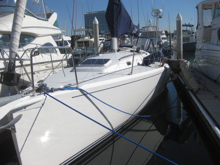 A white boat is tied to a dock in a marina