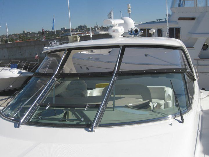 A white boat with a large windshield is parked in a marina