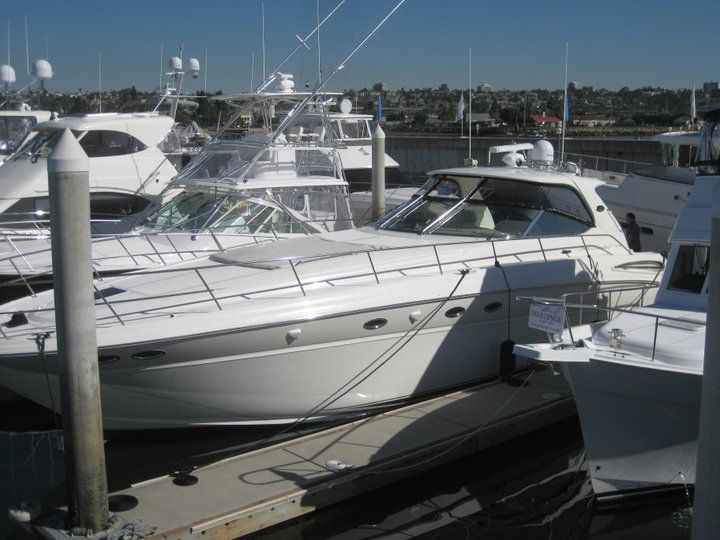 A row of boats are docked at a marina on a sunny day