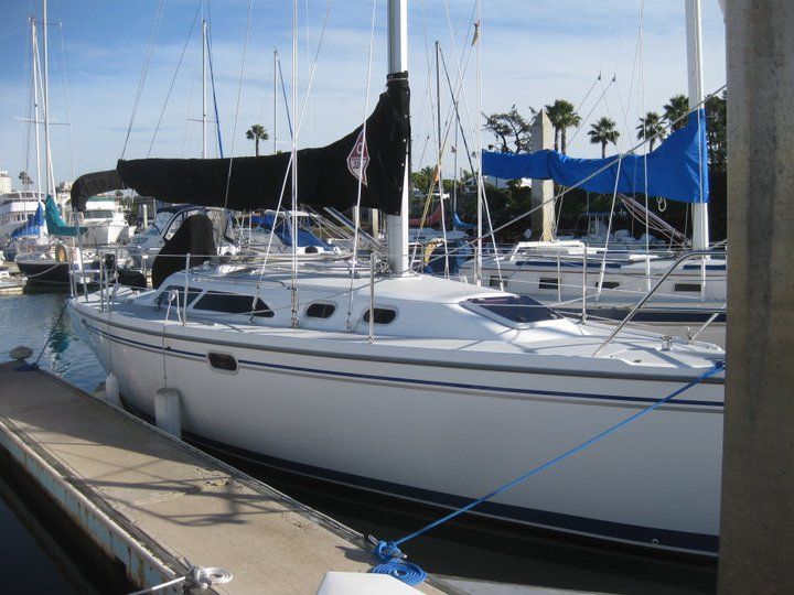 A white sailboat is docked at a marina