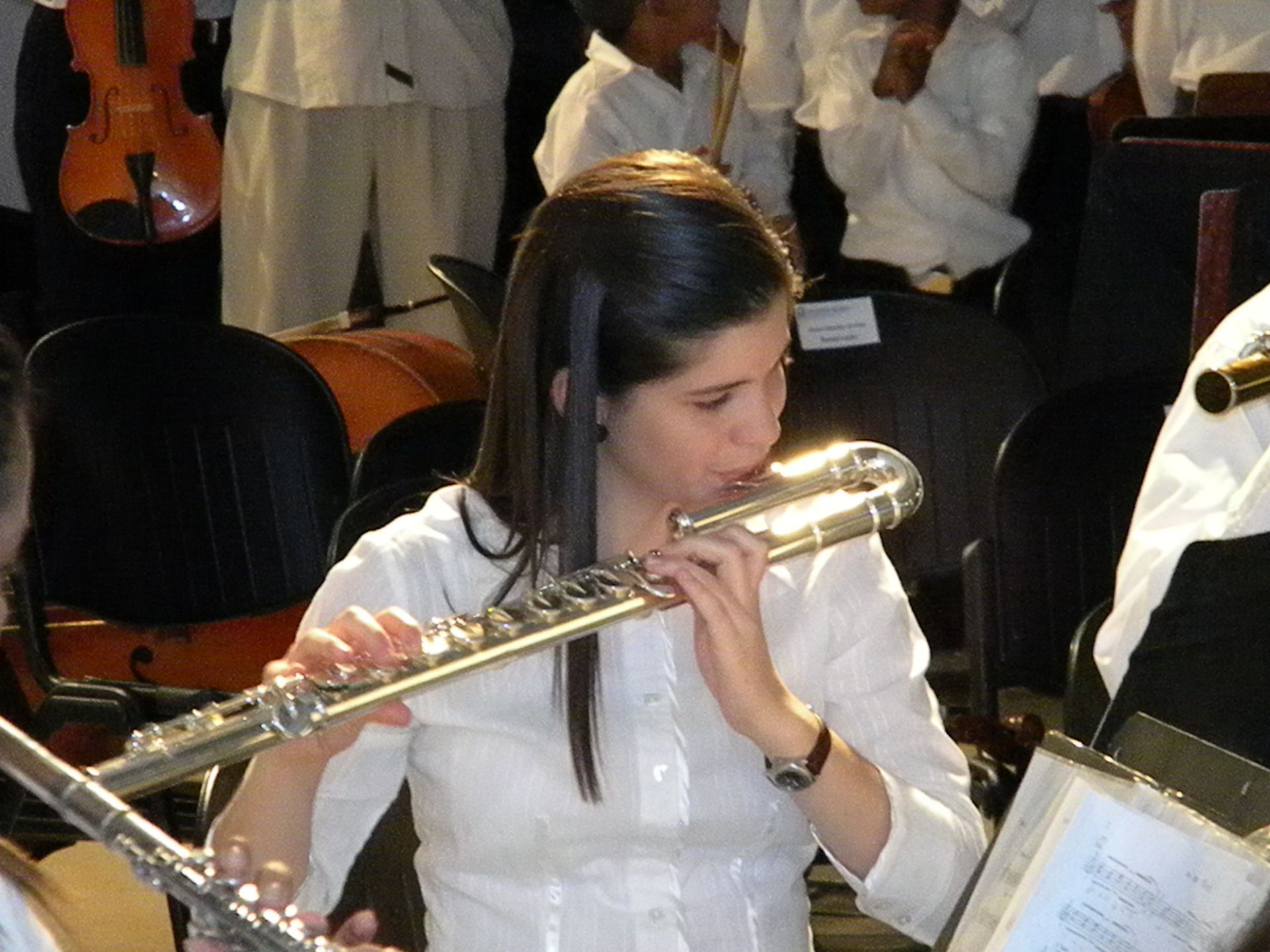 A woman is playing a flute in an orchestra