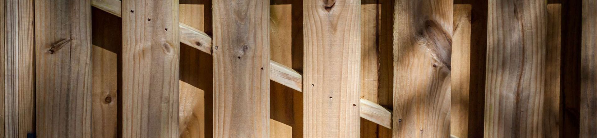 A close up of a wooden fence with a shadow on it.