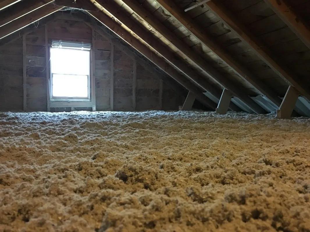 An attic with a lot of insulation and a window