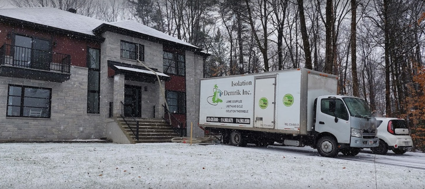 A white truck is parked in front of a house in the snow.