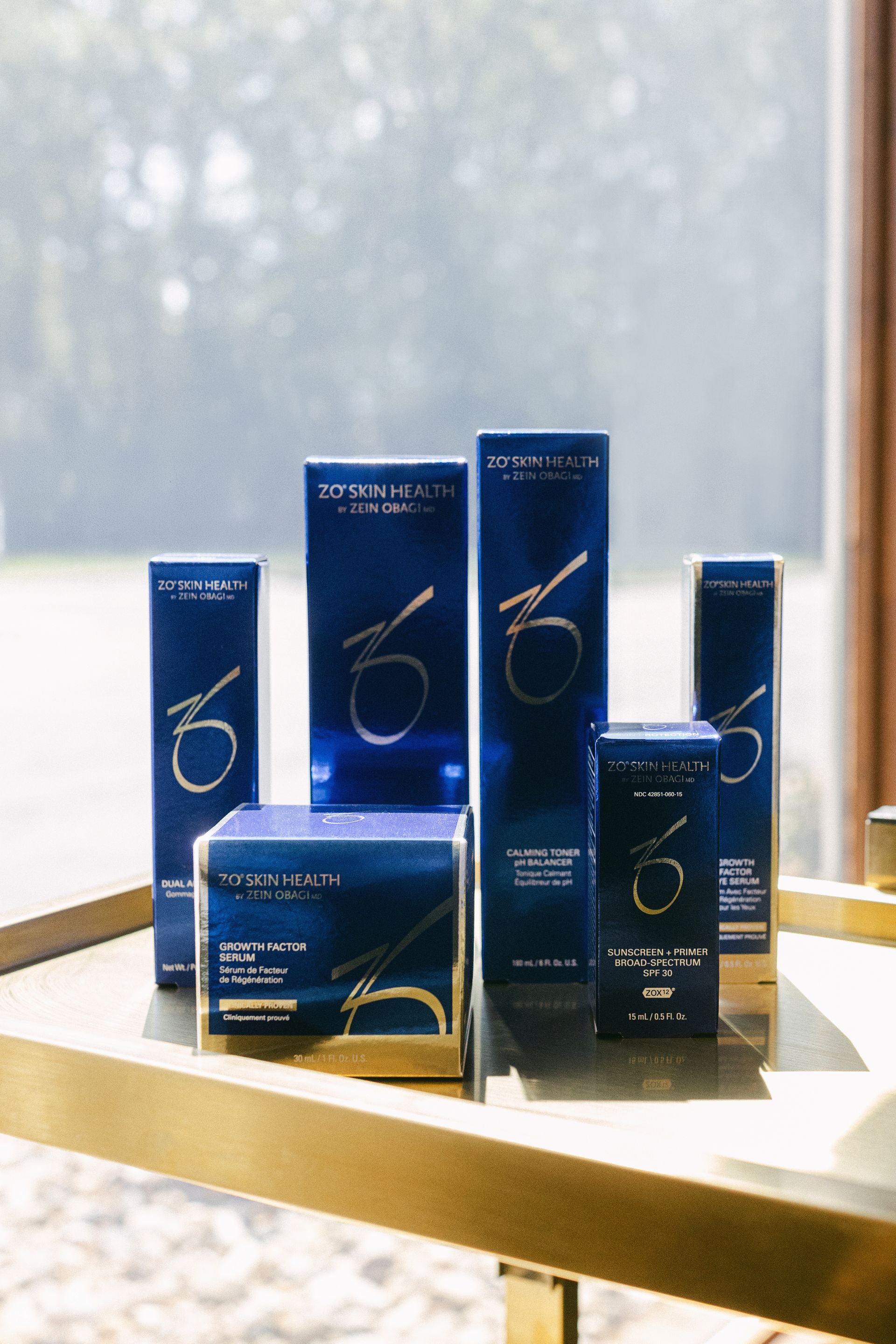 Blue cosmetic product boxes and bottles arranged on a sunlit windowsill.