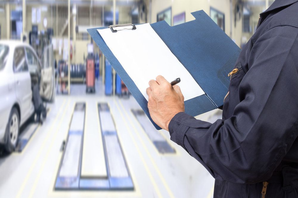 A Mechanic Is Writing On A Clipboard In A Garage — TBR Mechanical in East Arm, NT