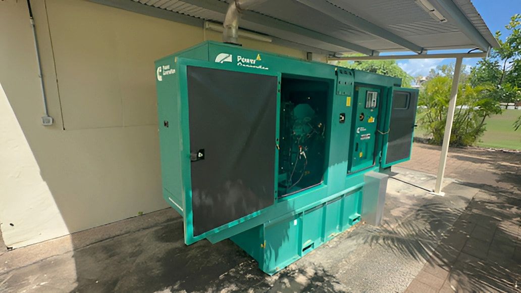 A Large Green Generator Is Sitting Under A Canopy In Front Of A Building — TBR Mechanical in East Arm, NT
