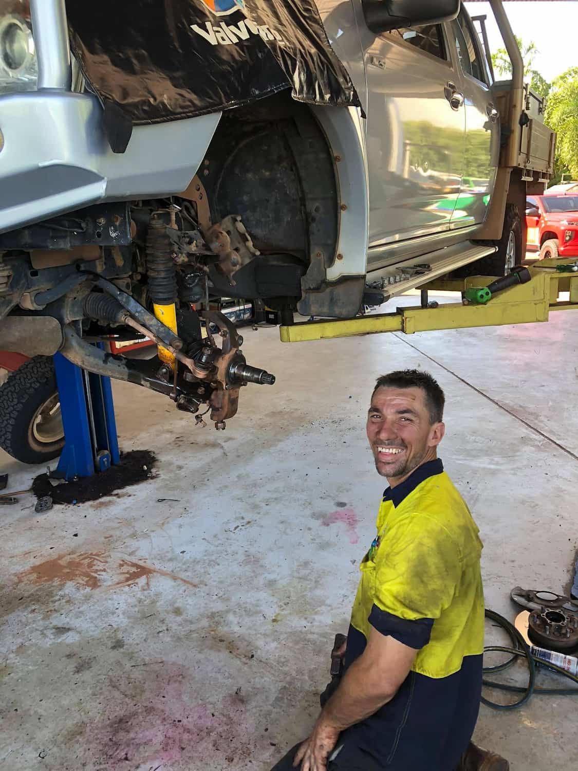 A Man Is Kneeling Down In Front Of A Truck On A Lift — TBR Mechanical in East Arm, NT
