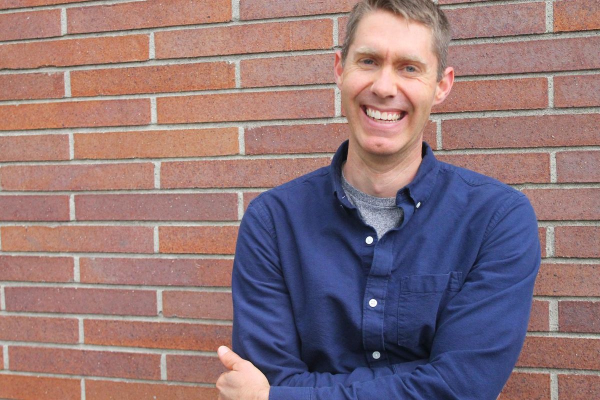 Steve smiling in a navy shirt in front of a brick wall